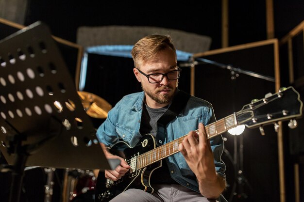 musica, persone, strumenti musicali e concetto di intrattenimento - chitarrista maschio che suona la chitarra elettrica in una prova in studio