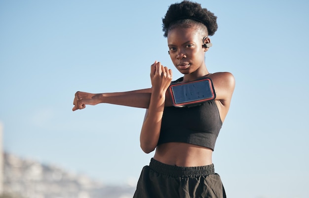 Musica ritratto e stretching con una donna nera che corre all'aperto su uno sfondo sfocato per cardio o resistenza Esercizio fisico o riscaldamento con un giovane atleta serio che si prepara all'allenamento