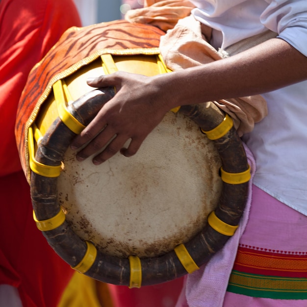 Musicista che suona con un Thavil durante una processione Tamil