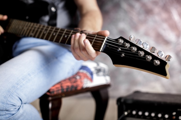 musicista che suona la chitarra elettrica su sfondo scuro. avvicinamento