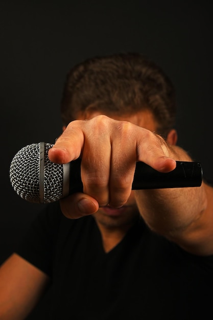 Musicista con il microfono mentre mostra il cartello rock sullo sfondo nero
