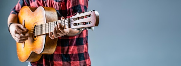 Musicista maschio che suona uno strumento musicale per chitarra Mans mani che suonano la chitarra acustica da vicino