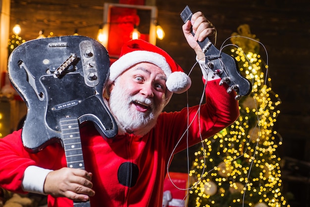 Musicista rock di babbo natale con chitarra elettrica rotta natale e festa di capodanno buone feste