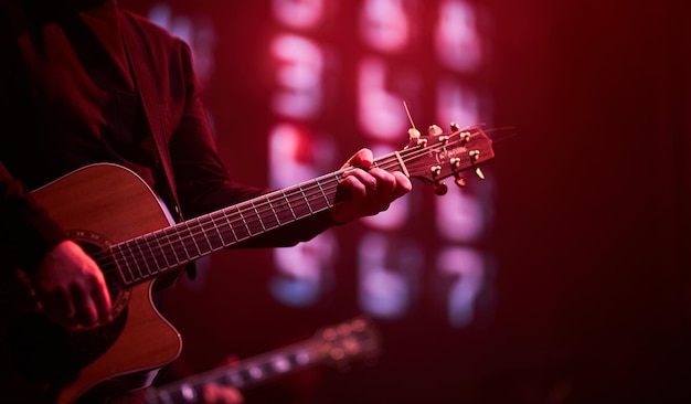 musicista suona la chitarra su uno sfondo rosso primo piano di mani e chitarra