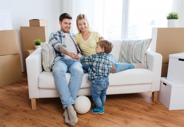 mutuo, persone, alloggio, trasloco e concetto immobiliare - famiglia felice con scatole che giocano a palla nella nuova casa