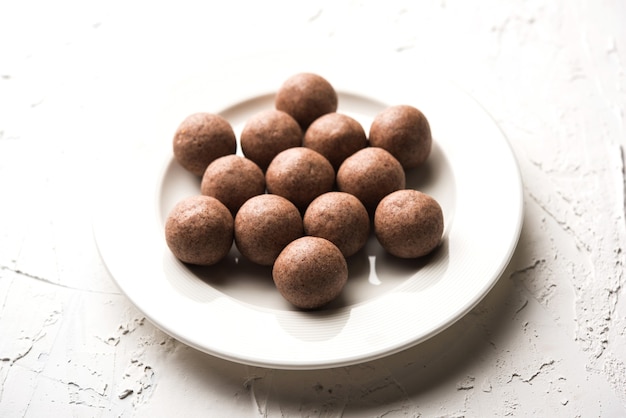 Nachni laddu o Ragi laddoo o palline fatte con miglio, zucchero e burro chiarificato. È un alimento salutare dall'India. Servito in una ciotola o piatto con crudo intero e polvere. Messa a fuoco selettiva