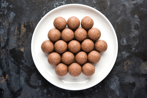 Nachni laddu o Ragi laddoo o palline fatte con miglio, zucchero e burro chiarificato. È un alimento salutare dall'India. Servito in una ciotola o piatto con crudo intero e polvere. Messa a fuoco selettiva