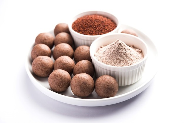 Nachni laddu o Ragi laddoo o palline fatte con miglio, zucchero e burro chiarificato. È un alimento salutare dall'India. Servito in una ciotola o piatto con crudo intero e polvere. Messa a fuoco selettiva