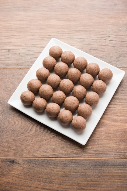 Nachni laddu o Ragi laddoo o palline fatte con miglio, zucchero e burro chiarificato. È un alimento salutare dall'India. Servito in una ciotola o piatto con crudo intero e polvere. Messa a fuoco selettiva