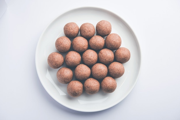 Nachni laddu o Ragi laddoo o palline fatte con miglio, zucchero e burro chiarificato. È un alimento salutare dall'India. Servito in una ciotola o piatto con crudo intero e polvere. Messa a fuoco selettiva