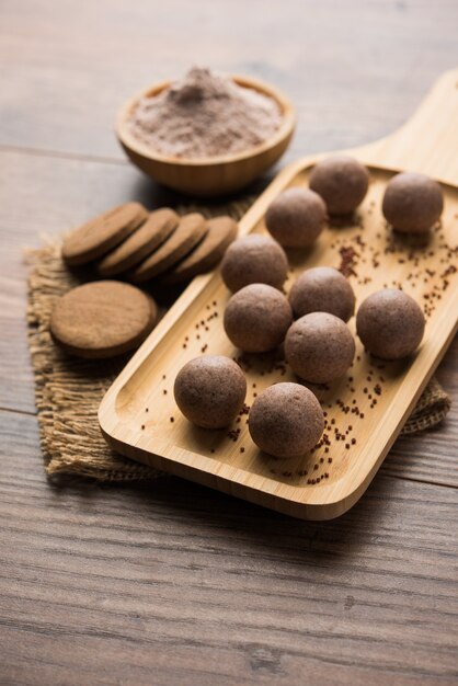 Nachni o Ragi laddu e biscotti o biscotti fatti con miglio, zucchero e burro chiarificato. È un alimento salutare dall'India. Servito in una ciotola o piatto con crudo intero e polvere