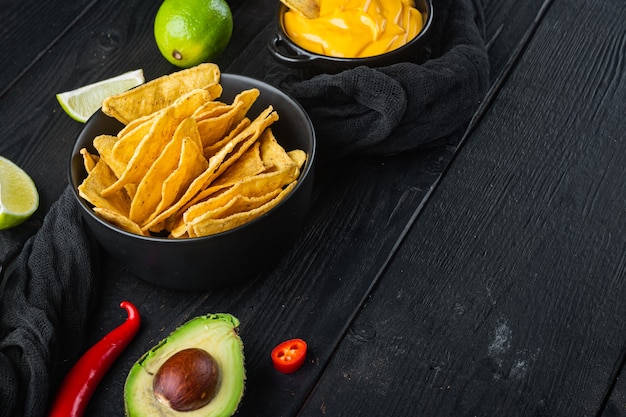 Nachos di patatine fritte di mais e salsa di immersione, sul tavolo di legno nero