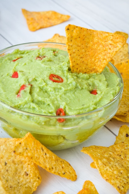 Nachos e guacamole in ciotola su legno bianco