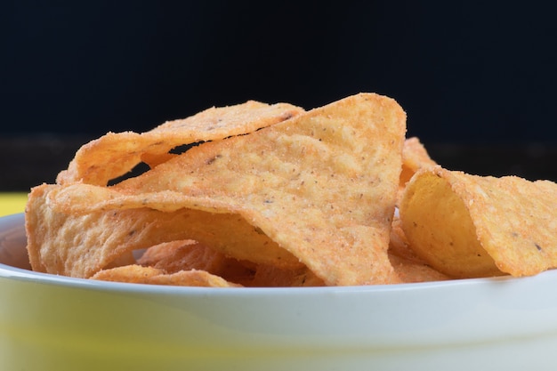 Nachos in una ciotola bianca con superficie nera.