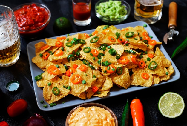 Nachos messicani di mais giallo con patatine fritte con jalapeno, guacamole, salsa di formaggio e salsa