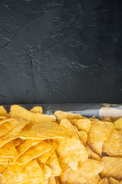 Nachos, triangolo tradizionale messicano pacchetto di antipasti di mais, sulla tavola nera, vista dall'alto o piatto