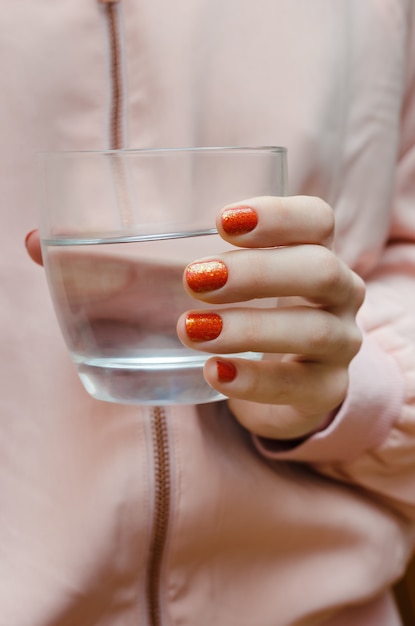 Nail art con glitter. Bella mano femminile con manicure arancione.