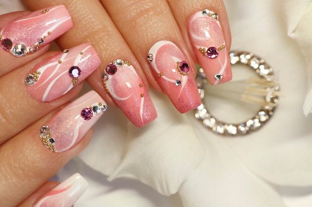 Nail design rosa chiaro con linee bianche, strass, glitter con gladiolo.