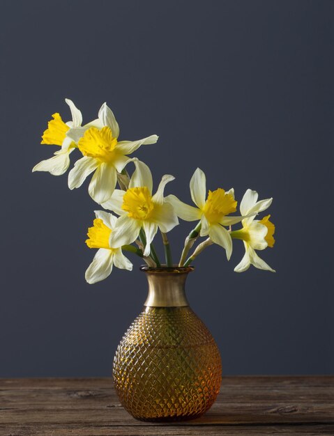 Narciso giallo in vaso su tavola di legno su sfondo scuro