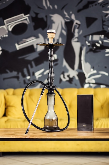 Narghilè sull'acqua si trova sul tavolo di legno con menu di tabacco Shisha Concept