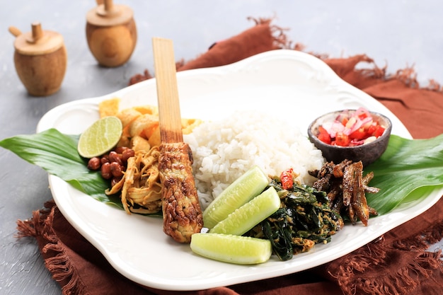 Nasi Campur Bali. Popolare pasto balinese a base di riso con vari contorni, servito insieme. Questo menu contiene Ayam Sisit, Sate Lilit, Saute Papaya Leaf e Sambal Matah.