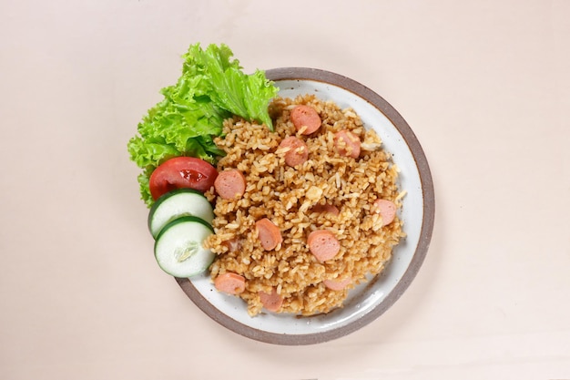 Nasi Goreng Sosis è riso fritto con salsicce guarnito con cetrioli freschi e fette di pomodoro.