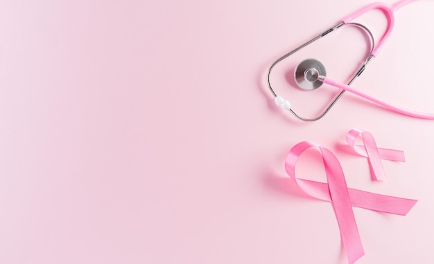 Nastri rosa e stetoscopio su sfondo pastello Simbolo della consapevolezza del cancro al seno delle donne