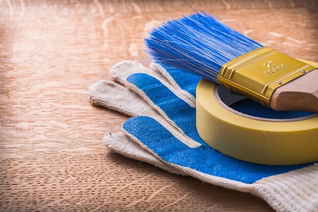 Nastro adesivo del condotto del pennello e guanti protettivi sul concetto di legno della costruzione del bordo