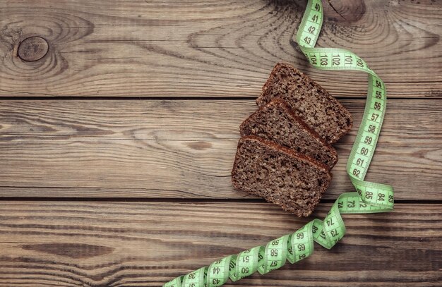 Nastro di misurazione e dieta pane di segale integrale su sfondo di legno Concetto di dieta dimagrante