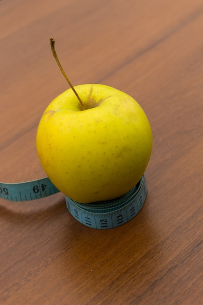 Nastro di misurazione e mela verde sulla tavola di legno. Concetto di dieta e stile di vita sano