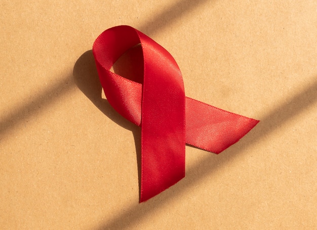 Nastro di raso rosso con anello come simbolo dell'hiv e giornata di sensibilizzazione contro l'AIDS alla luce del giorno del primo dicembre sull'artigianato ...