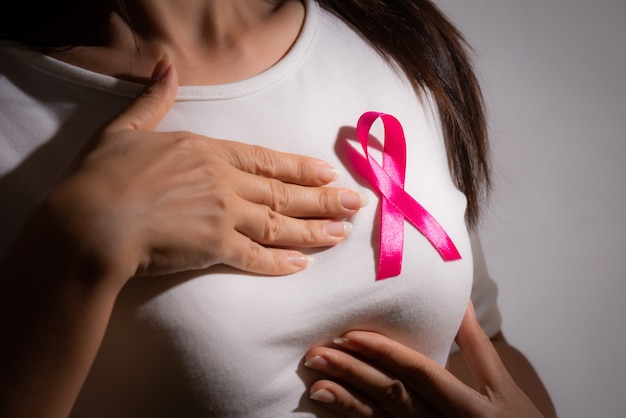 Nastro distintivo rosa sul petto della donna per sostenere il cancro al seno. Assistenza sanitaria.