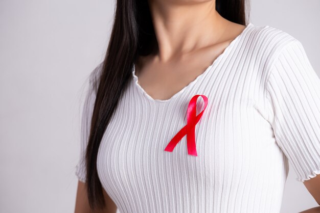 Nastro distintivo rosso sul petto della donna per l'AIDS Day. Concetto di assistenza sanitaria.