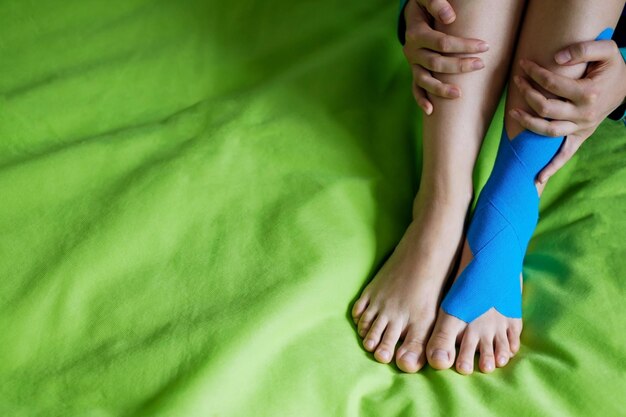 Nastro elastico terapeutico blu applicato alla gamba sinistra del paziente
