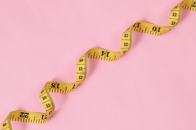 nastro metrico per persone obese su uno sfondo rosa messa a fuoco morbida
