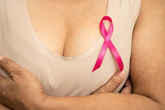 Nastro rosa cancro al seno presso la signora asiatica senior per sostenere il simbolo della consapevolezza della Giornata mondiale del cancro al seno