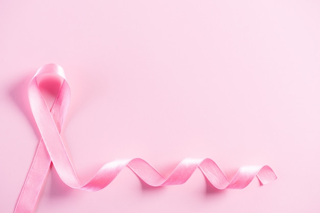Nastro rosa su carta rosa pastello per supportare la consapevolezza del cancro al seno