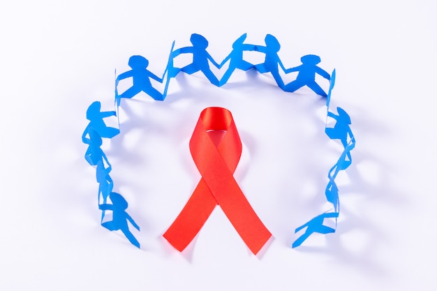 Nastro rosso con catena di persone in carta tagliata. Giornata mondiale dell'Aids.