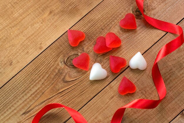 Nastro rosso e cuori su uno sfondo di legno Cuori rossi Candy Love concept San Valentino Copia spazio per le iscrizioniVista dall'alto