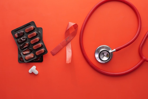 Nastro rosso HIV e stetoscopio su sfondo rosa