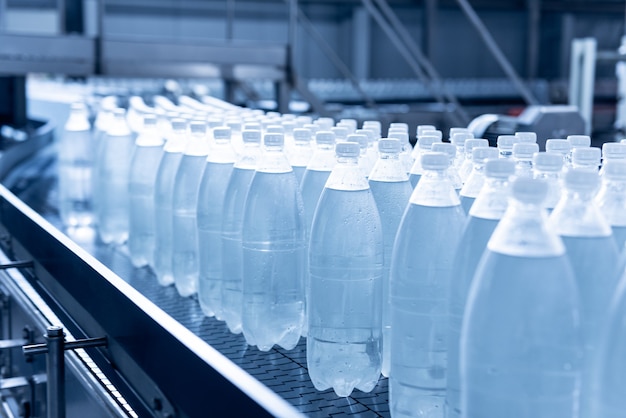 Nastro trasportatore con bottiglie di acqua potabile in un moderno impianto di bevande.