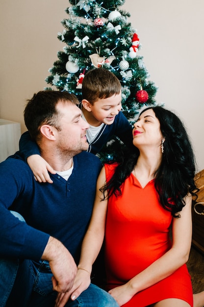 Natale a casa vicino all'albero di Natale. Mamma, papà e figlio felici che si godono insieme le loro vacanze.