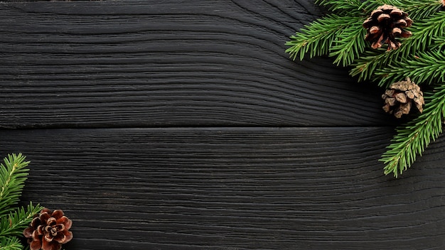 Natale Abete rami e pigne su uno sfondo di legno nero.