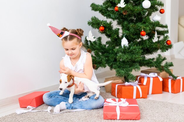 Natale, animali domestici e concetto di vacanze - Bambino con cappello da Babbo Natale con un cucciolo di jack russell terrier.