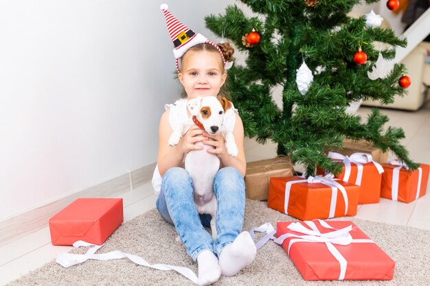 Natale, animali domestici e concetto di vacanze - Bambino con cappello da Babbo Natale con un cucciolo di jack russell terrier.