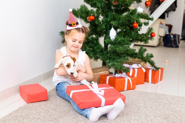 Natale, animali domestici e concetto di vacanze - Bambino con cappello da Babbo Natale con un cucciolo di jack russell terrier.