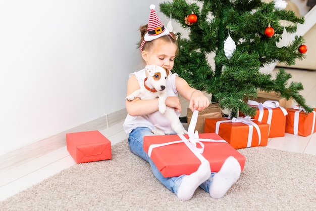 Natale, animali domestici e concetto di vacanze - Bambino in cappello della santa con un cucciolo di jack russell terrier