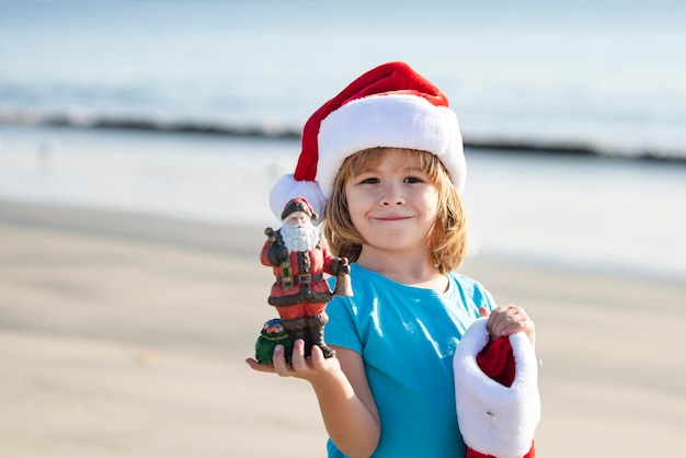 Natale bambino concetto di vacanza santa kid sul tramonto mare estate caldo capodanno mare sfondo holid...