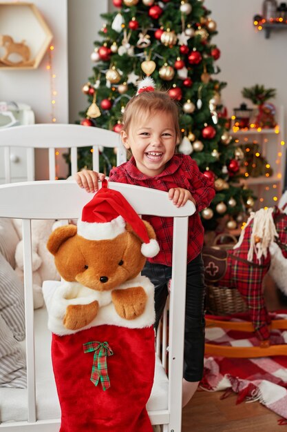 Natale bambino. Piccola ragazza sorridente in letto bianco nella stanza dei bambini