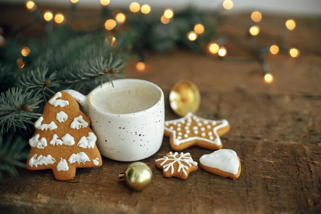 Natale biscotti di pan di zenzero caffè rami di abete su sfondo di luci bokeh su legno rustico